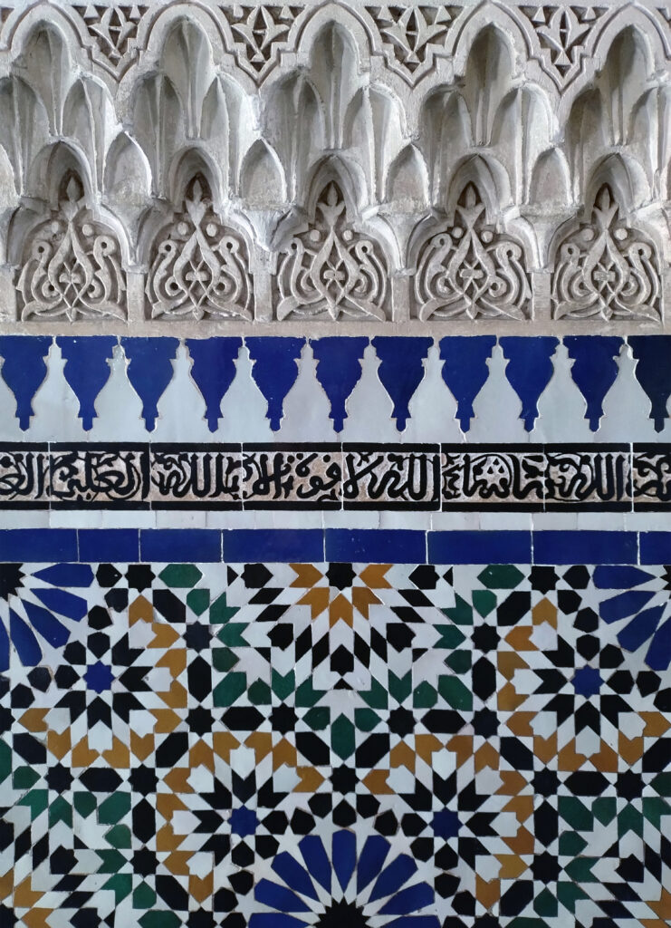 Particolare del decoro sulle pareti di Palais de la Bahia. In sequenza zellij, arabeschi e muqarnas.